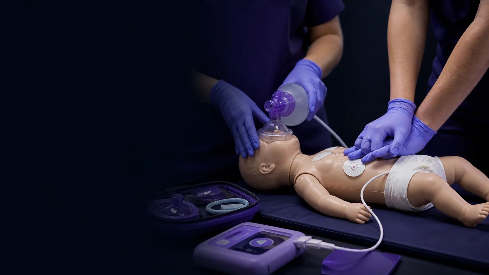Healthcare providers practicing resuscitation skills with an infant training manikin